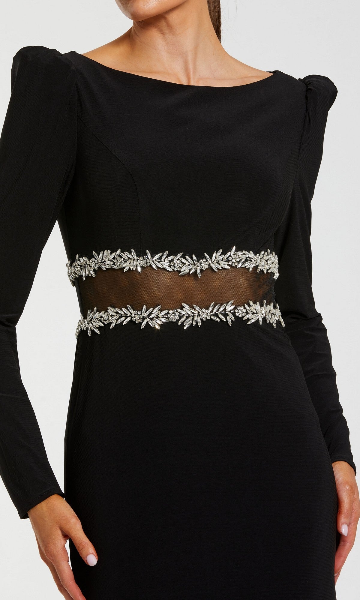 A woman wearing the Mac Duggal 27695 long formal dress—a black stretch jersey gown featuring long sleeves, sheer midsection, puff shoulders, and silver leaf embellishments at the waist for an elegant evening look.